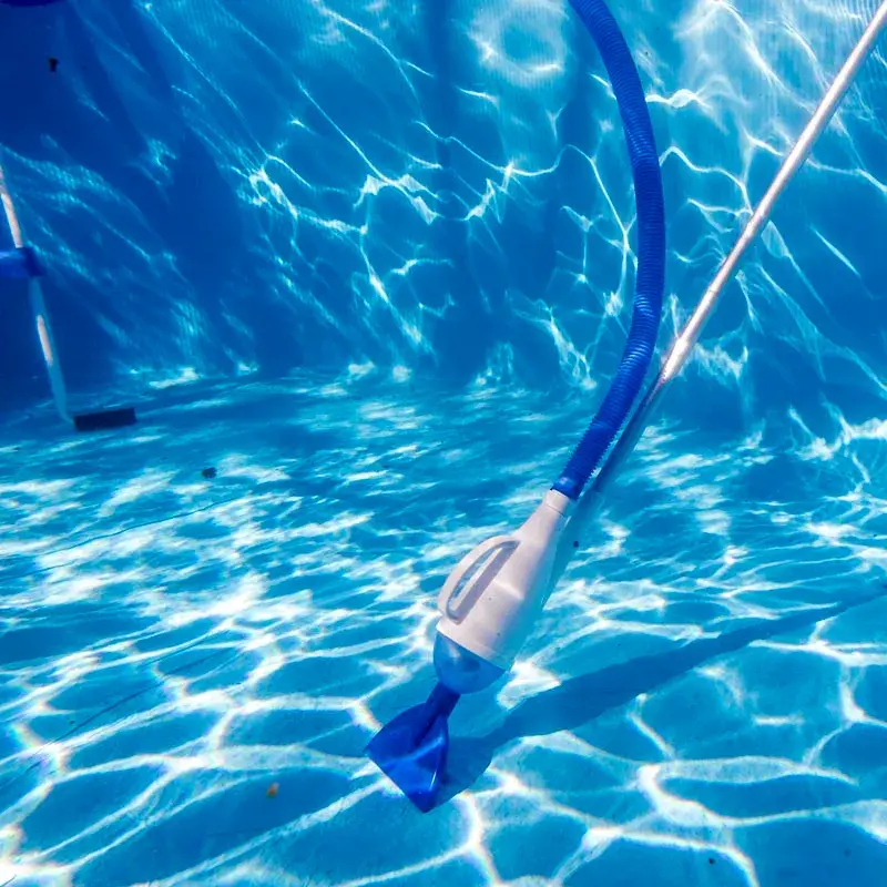 08011a-3 | PisciManía Pool cleaning tool with a blue hose submerged in bright blue pool water.