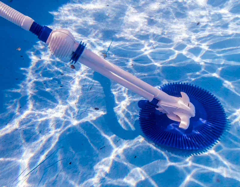 19001-3 | PisciManía Blue circular pool vacuum head attached to a white pole lies in a clear blue pool water.