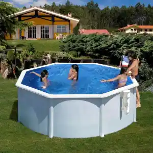 piscina-gre-bora-bora-circular-acero-chapa-blanca-2 | PisciManía Backyard scene with a large blue above-ground pool, children swimming, and two adults at the pool edge; a yellow house and green hedge in the background.