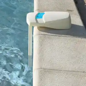 770270-2 | PisciManía White plastic pool-edge device mounted on the coping with a blue label, positioned beside clear blue pool water.