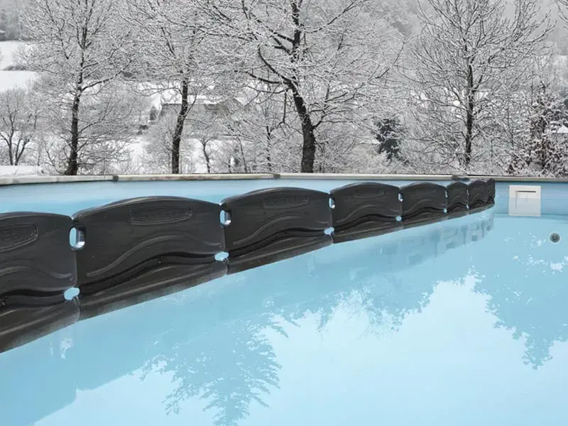 40580-3 | PisciManía Snowy outdoor scene with a blue swimming pool and a black modular pool cover along the edge.