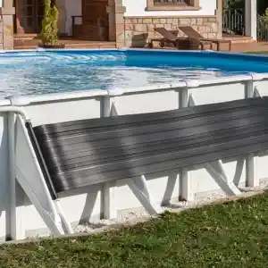 ar2069-1 | PisciManía Above-ground pool with a black solar cover rolled on a white frame, near a stone-clad house with arches and lounge chairs on the patio.