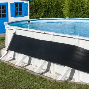 ar2069-2 | PisciManía Above-ground pool with a black safety cover partially rolled across the side, white frame, blue water, and a blue-shuttered shed behind a green hedge.