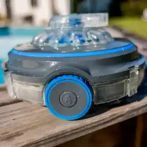 rbr75-3 | PisciManía Close-up of a gray circular device with a bright blue ring and blue accents, sitting on a wooden deck near a pool.